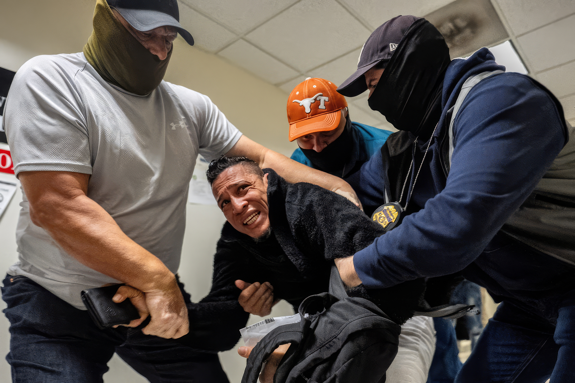 A father being forcibly detained by masked officers